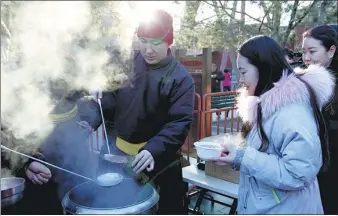  ?? ZHANG WEI / CHINA DAILY ?? People line up at Beijing’s Yonghe Lama Temple for free Laba rice porridge on Sunday. One tradition says that eating the porridge will bring happiness in the coming year.