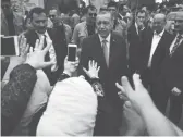  ??  ?? Le président turc Recep Tayyip Erdogan (C) quittant le bureau de vote après avoir glissé son bulletin dans l’urne, hier, à Istanbul