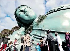  ??  ?? The Reclining Buddha at Nanzoin Temple in Sasaguri, Japan, is cleaned with bamboo