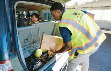  ?? ROSS D. FRANKLIN/AP ?? A St. Mary’s Food Bank volunteer fills a vehicle with food June 29 in Phoenix. More Americans are turning to food banks.