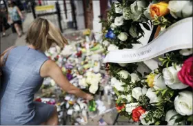  ?? JOHN MINCHILLO — THE ASSOCIATED PRESS ?? Mourners bring flowers to a makeshift memorial Tuesday for the slain and injured in the Oregon District after a mass shooting that occurred early Sunday morning, in Dayton.