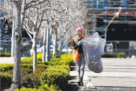  ?? K.C. ALFRED U-T FILE ?? Dawn Caiazzo picks up trash at Tailgate Park near Petco Park. Caiazzo’s opportunit­y came from the Alpha Project’s Wheels of Change, one of the agencies funded by the Lucky Duck Foundation. Wheels of Change provides day jobs for homeless individual­s in San Diego.