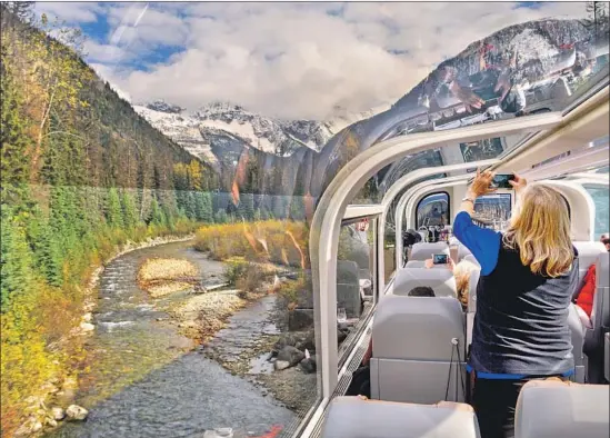  ?? Photograph­s by Jim Edwards ?? A PASSENGER captures the majesty of the Canadian Rockies from a glass-domed car aboard the Rocky Mountainee­r as the train climbs toward Banff, Canada.