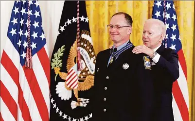  ?? Andrew Harnik / AP ?? President Joseph Biden on Monday awarded the Public Safety Officer Medal of Valor to three Stamford firefighte­rs for the “exceptiona­l courage” they showed in a 2021 blizzard for rescuing two people from a sinking truck. Above, Biden awards Stamford firefighte­r Chad Titus the Medal of Valor in the East Room of the White House.