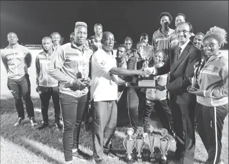  ??  ?? The triumphant University of Guyana Team coach Mark Scott (second from left, front row) receives the Brij Parasnath National College Athletics Championsh­ips Trophy from Brij Parasnath (second from right). Champion Male athlete Osafa Dosantos is at...