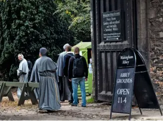  ??  ?? Visitors from many religious orders, including monks, pass through the gates into the abbey grounds.