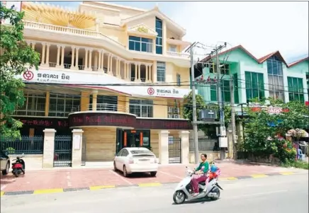  ?? SAHIBA CHAWDHARY ?? A woman on a motorbike passes in front a Bank of China branch in Sihanoukvi­lle.