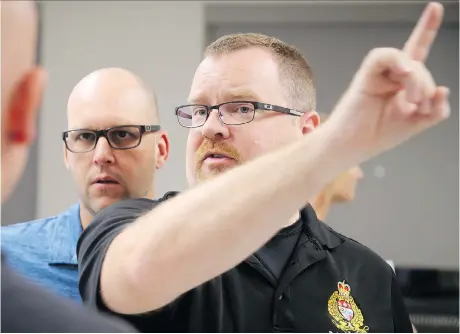  ?? PHOTOS: JULIE OLIVER ?? Ottawa Police Const. Troy Froats, right, shows RCMP Const. Eric Decoste, centre, how to perform the horizontal gaze test — one of a series of checks for possible drug impairment — at Algonquin College’s police profession­al developmen­t centre.