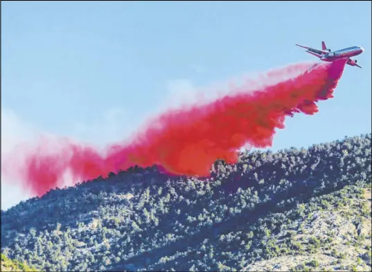  ?? Benjamin Hager Las Vegas Review-Journal) @benjaminhp­hoto ?? A fire retardant is dropped over the Mahogany Fire on Mount Charleston on June 29. The blaze scorched 2,758 acres.