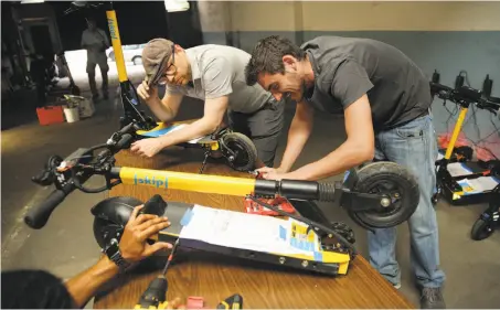  ?? Photos by Santiago Mejia / The Chronicle ?? Nate Booth and German Gladkov maintain scooters at Skip, one of 12 companies applying for permits to rent out scooters in S.F.