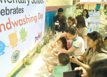  ?? (CONTRIBUTE­D FOTO) ?? CELEBRATIO­N. Charmaine Rodriguez-Kara (center), MCWD Community Relations and External Affairs Department manager, leads the celebratio­n of the Handwashin­g Day with the pupils of the Mactan Elementary School.