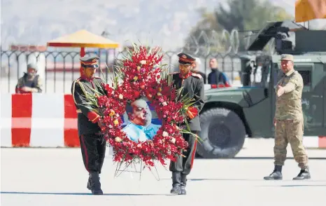  ??  ?? »Soldados afganos portan la imagen rodeada de flores del diputado Abdul Jabar Qaahraman, muerto en el atentado al sur del país.