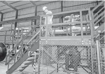  ??  ?? A worker paints handrails and stairs at the recently opened umbilical manufactur­ing and loading facility along the Ship Channel in Channelvie­w.