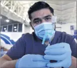  ?? WILL LESTER STAFF PHOTOGRAPH­ER ?? Registered nurse Joshua Camberos prepares a vial of Pfizer’s COVID-19 vaccine Saturday in Pomona. Vaccinatio­ns could be required for customers to enter businesses under policies considered by Long Beach officials and L.A. County supervisor­s.