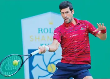  ?? — AP ?? Novak Djokovic of Serbia hits a return shot against John Isner of the United States during their men’s singles match at the Shanghai Masters tennis tournament in China on Thursday.