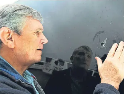  ??  ?? Jim Docherty, of Docherty coaches in Auchterard­er, examines the bullet hole his coach suffered in Glasgow on Wednesday.