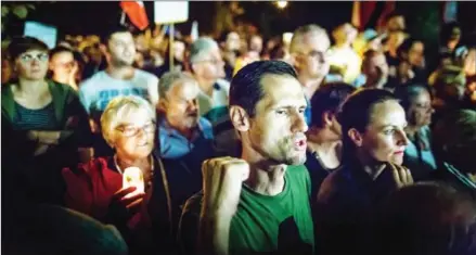  ?? WOJTEK RADWANSKI/AFP ?? Protesters hold candles and shout slogans during a demonstrat­ion outside the Polish parliament as Polish senators decide on a new bill changing the judiciary system, on July 21.