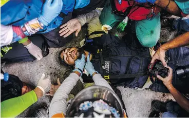  ?? FEDERICO PARRA / AFP / GETTY IMAGES ?? A journalist injured in clashes between demonstrat­ors and riot police in Caracas on Wednesday is helped by volunteer medics.