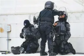  ?? AP PHOTO/JOHN MINCHILLO ?? A police officer flushed the eyes of another officer with water after a confrontat­ion with rioters at the Capitol in Washington on Jan. 6