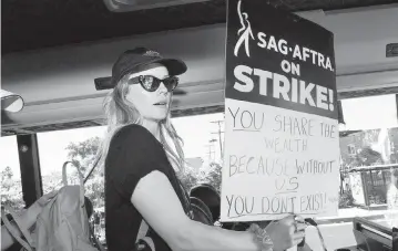  ?? VALERIE MACON TNS ?? A member of the SAG AFTRA bargaining committee steps out the bus dedicated to guild members traveling to picket lines to join members of the Writers Guild of America and the Screen Actors Guild outside Paramount Studios in Los Angeles on July 14, 2023. Tens of thousands of Hollywood actors went on strike, effectivel­y bringing the giant movie and television business to a halt as they joined writers in the first industry-wide walkout for 63 years.