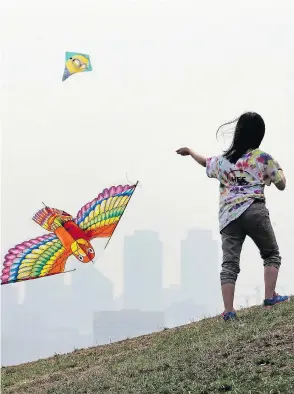  ?? ELAINE THOMPSON/THE ASSOCIATED PRESS ?? A nine-year-old girl tries to get her kite in the air as a smoky haze obscures her urban environmen­t.