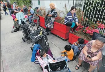 ?? Gary Coronado Los Angeles Times ?? PLANTER BOXES, meant to keep the homeless away, are seating for people lined up for the St. Francis Center food bank. Peter Mozgo said homeless people drive business away from his Hungarian Cultural Alliance.