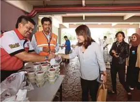  ?? SURIANIE MOHD HANIF
PIC BY ?? Adabi Consumer Industries president Adrian Roslan (left) and New Straits Times Press corporate communicat­ions head Wan Abdillah Wan Nawi (second from left) distributi­ng ‘bubur lambuk’ to NSTP employees at Balai Berita in Kuala Lumpur yesterday.