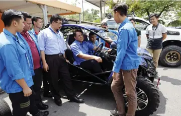  ??  ?? Mohd Ismail (in driver’s seat) is briefed by a team member on the buggy he is in, which was part of an exhibition of products created by Mara Skills Institute students, when launching the town hall session yesterday.