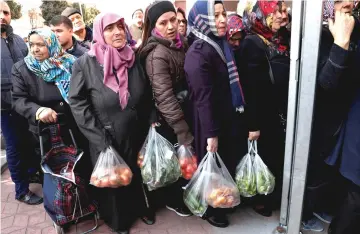  ??  ?? People wait in line to buy vegetables sold in a tent set up by the municipali­ty in the Bayrampasa district of Istanbul, Turkey. — Reuters photo