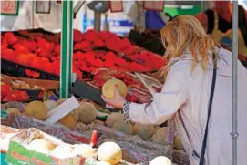  ?? AP PHOTO/MARTIN MEISSNER ?? A woman checks the price of a water melon Wednesday in Essen, Germany.