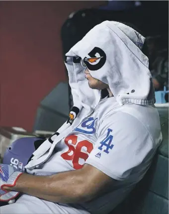  ?? Ross D. Franklin Associated Press ?? WITH HIS HEAD covered, Yasiel Puig sits in the dugout after flying out in the ninth inning. Puig’s sloppy defensive play in the first inning set the tone for the Dodgers, who were swept in Arizona.