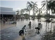  ?? EDUARDO VERDUGO/ THE ASSOCIATED PRESS ?? People look for valuables in a store’s flooded parking lot in Punta Diamante, south of Acapulco, after a tropical storm hit the area with full force. At least 80 people have died.