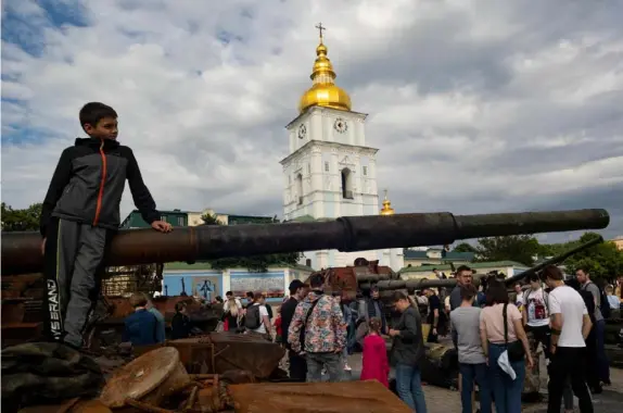  ?? Stephen Zenner photos/The Blade ?? A boy leans on burned out tank in front of St. Michael’s Golden-Domed Monastery in Kyiv, Ukraine, on June 4. Enemy tanks and engines of war are put on display all around the city for people to come and inspect.