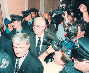  ?? KEITH GOSSE THE CANADIAN PRESS FILE PHOTO ?? John Crosbie, centre, then federal fisheries minister, leaves a St. John’s hotel surrounded by security and media after announcing a two-year moratorium on cod fishing on July 2, 1992.