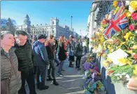  ?? PAUL HACKETT / REUTERS ?? Onlookers view floral tributes on the wall surroundin­g the Houses of Parliament in London on Saturday.