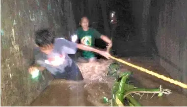  ?? PHOTOGRAPH COURTESY OF PCG ?? RESIDENTS wade through floodwater in Jolo, Sulu on Sunday night, using as guide a rope installed by the Philippine Coast Guard.