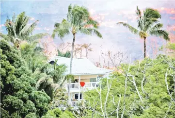  ??  ?? Lava flows near a house on the outskirts of Pahoa during ongoing eruptions of the Kilauea Volcano. — Reuters photo