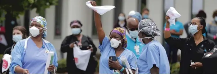  ?? AP PHOTO/GERALD HERBERT ?? Healthcare workers at New Orleans East Hospital wave handkerchi­efs and dance to a jazz serenade by the New Orleans Jazz Orchestra outside the hospital as a tribute for their care for COVID-19 patients on May 15, 2020. Months later, we’re still celebratin­g the good deeds of healthcare heroes, essential workers and neighbors serving those around them.