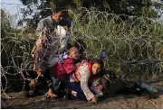  ?? Reuters) (Bernadett Szabo/ ?? SYRIAN MIGRANTS cross under a fence as they enter Hungary illegally at the border with Serbia.