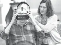  ?? Orlando Sentinel/TNS ?? BELOW: Encore at Avalon Park Executive Director Kim Edwards, right, helps resident John Auchter with a headset to view a Mynd Virtual Reality video on July 12, 2017. Auchter suffers from dementia.