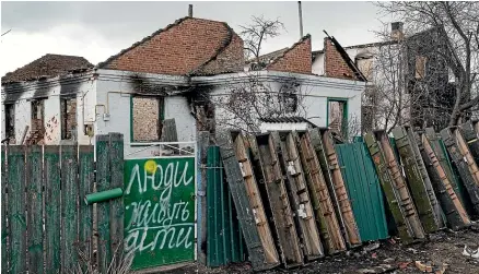  ?? GETTY IMAGES ?? The gate with writing on it next a destroyed building in Andriivka, Ukraine. The writing says ‘‘People, Kids live here’’.