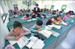  ?? LI XIN / XINHUA ?? Children in Beijing do their homework after class while waiting for their parents to collect them.