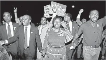  ?? Linda Schaeffer Associated Press ?? LONG POLITICAL CAREER John Lewis, front left, holds hands with his wife and advisor, Lillian, as he leads backers to a party after he defeated Julian Bond in a 1986 runoff for Georgia’s 5th Congressio­nal District. He would serve 17 terms.