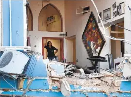  ?? Photograph­s by Hussein Malla Associated Press ?? A WOMAN examines a Beirut restaurant a day after the blast. “I’ve never seen the country so damaged,” even during wartime, a volunteer aid worker said.