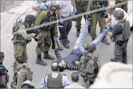  ?? NASSER SHIYOUKHI / ASSOCIATED PRESS ?? Israeli soldiers lift a wounded Palestinia­n man Monday in the West Bank city of Hebron. The Israeli army said its forces shot a Palestinia­n who tried to stab an Israeli soldier near a sensitive holy site in the city.