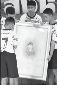  ?? AP/VINCENT THIAN ?? Boys who were rescued from a flooded cave show their respect and thanks as they hold a portrait of Saman Gunan, the retired Thai SEAL diver who died during their rescue attempt, Wednesday during a news conference in Chiang Rai, northern Thailand.