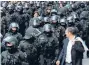  ?? Photo: REUTERS ?? Safety in numbers: Riot police accompany protestors headed for the opening of a new bank skyscraper.