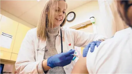  ?? TYGER WILLIAMS/PHILADELPH­IA INQUIRER ?? Kelly Moran, a nurse practition­er from Philadelph­ia, gives a flu shot to a patient at a CVS Minute Clinic in January 2020.