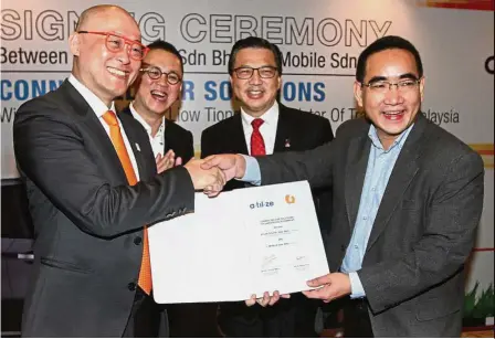  ??  ?? Smart partnershi­p: U Mobile CEO Wong Heang Tuck (left) exchanging documents with Lim. With them are Green Packet Bhd founder C.C. Puan (second from left) and Transport Minister Datuk Seri Liow Tiong Lai. By FINTAN NG fintan@thestar.com.my
