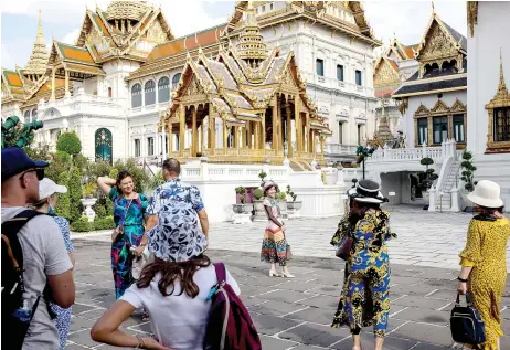  ?? — AFP file photo ?? Tourists gather and taking pictures in the grounds of the Grand Palace in Bangkok.